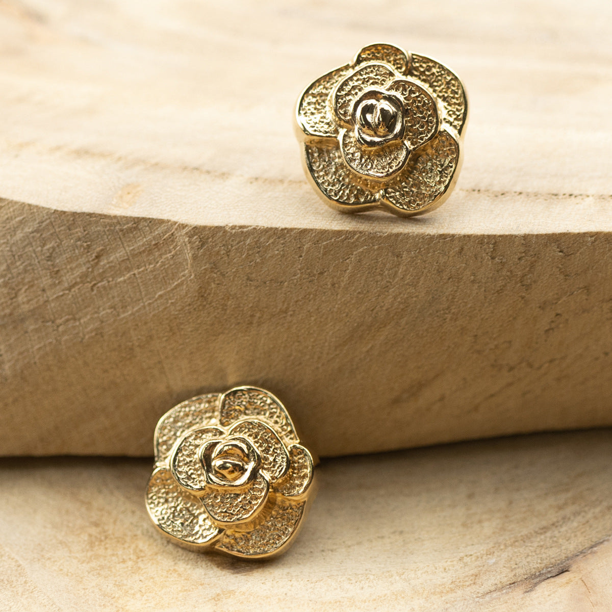Two gold rose metal buttons, front views with embossed petals and central ring