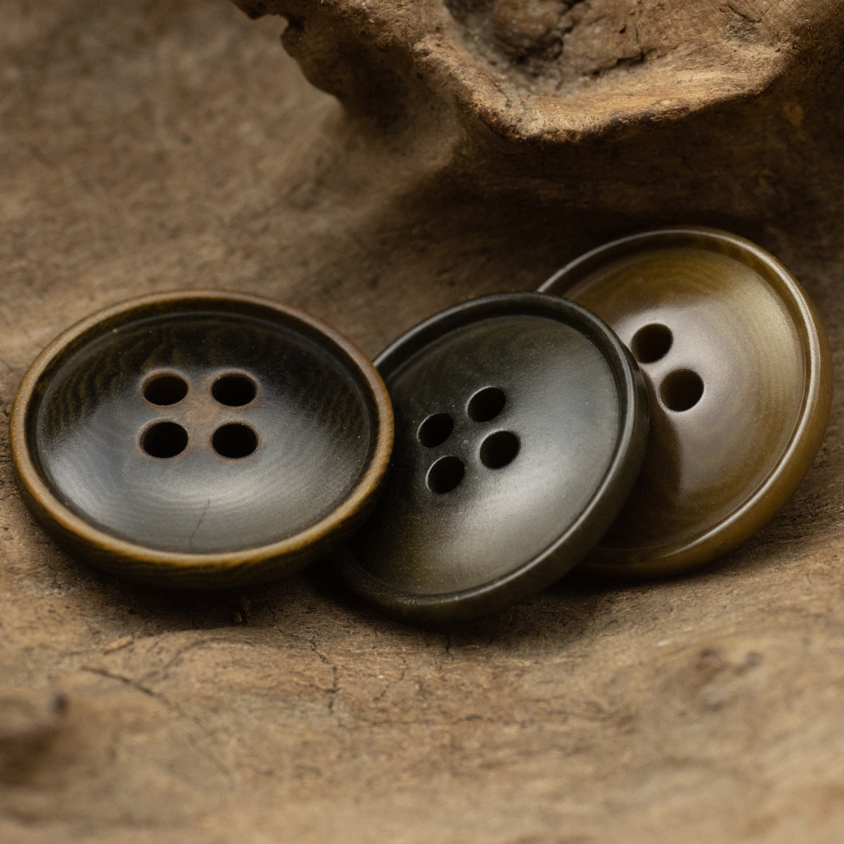 Three round 4-hole vintage natural buttons in dark olive and brown tones