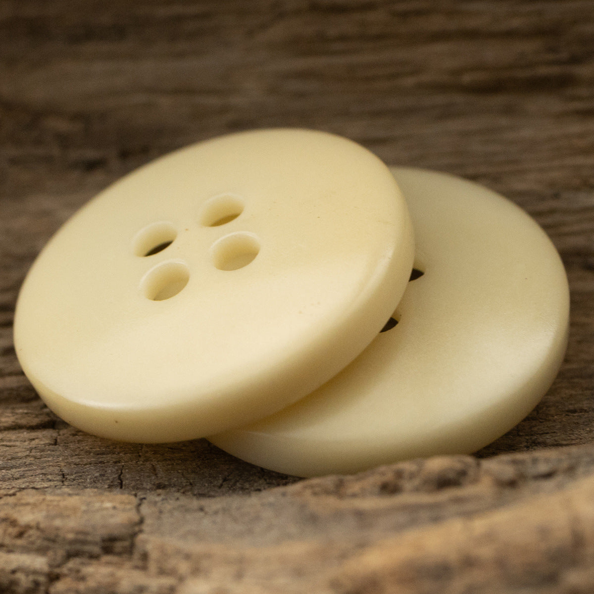 Light yellow 18mm fruit buttons with 4 sewing holes, close-up on stacked pair