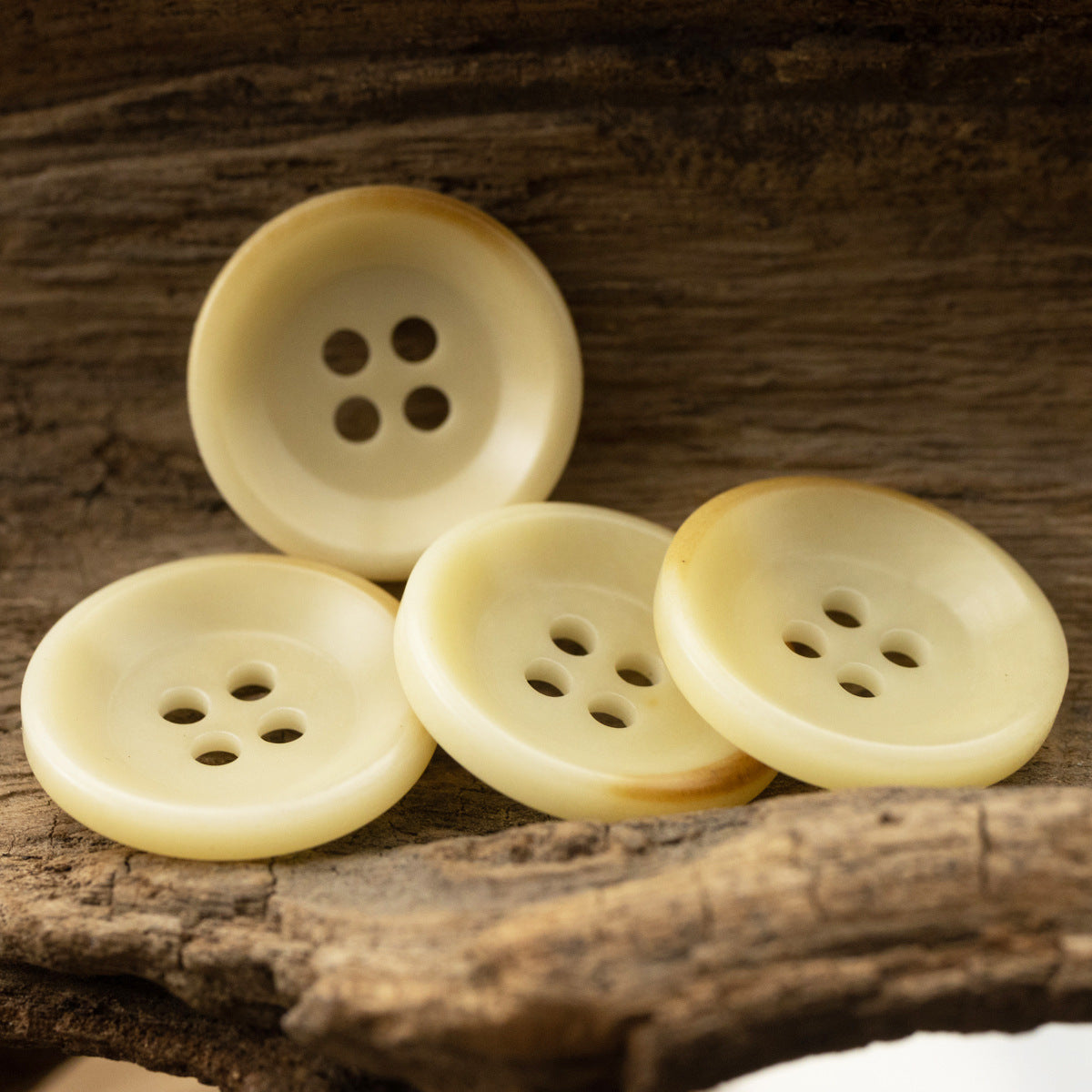 Group of 18mm light yellow fruit buttons with 4-hole sewing layout on wood