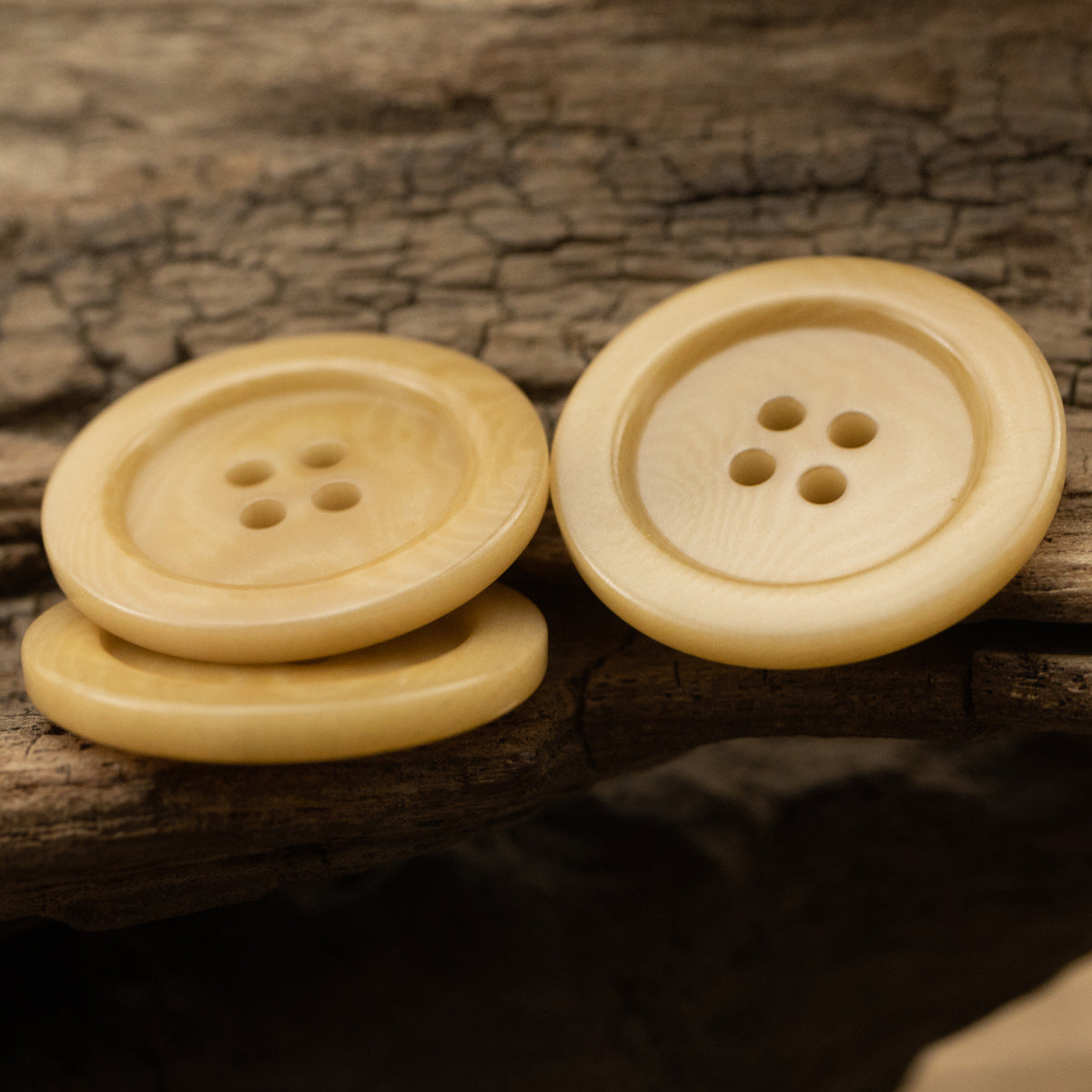 Pair of light yellow buttons with four holes each, round smooth front