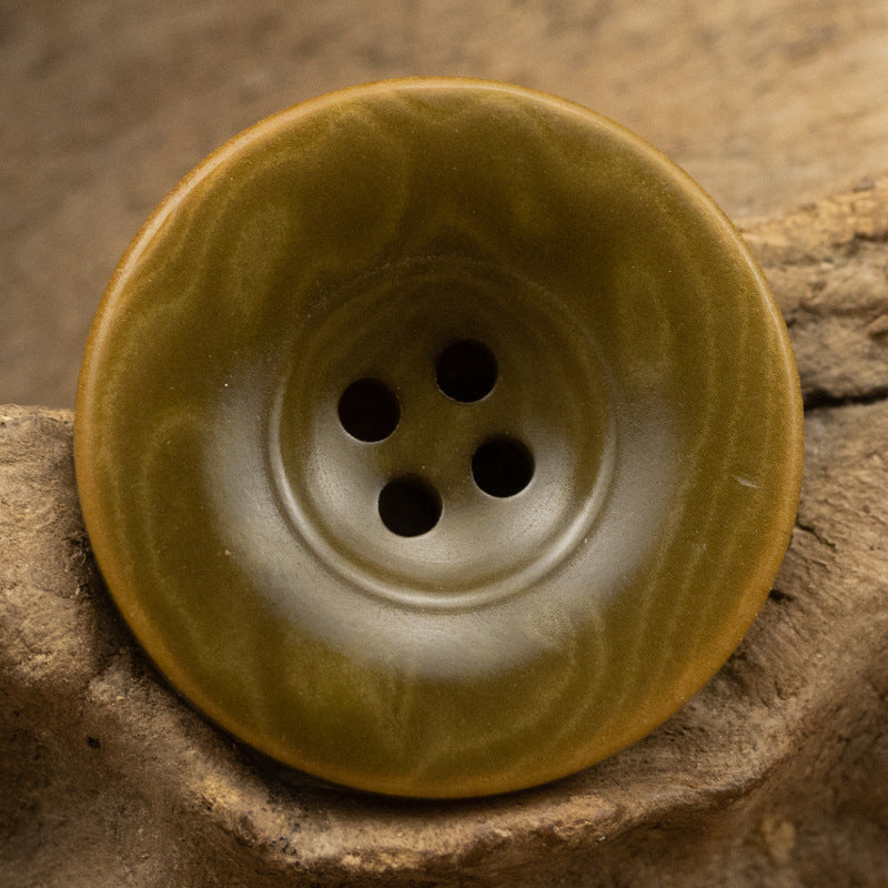 Green natural fruit button with four holes, close-up front