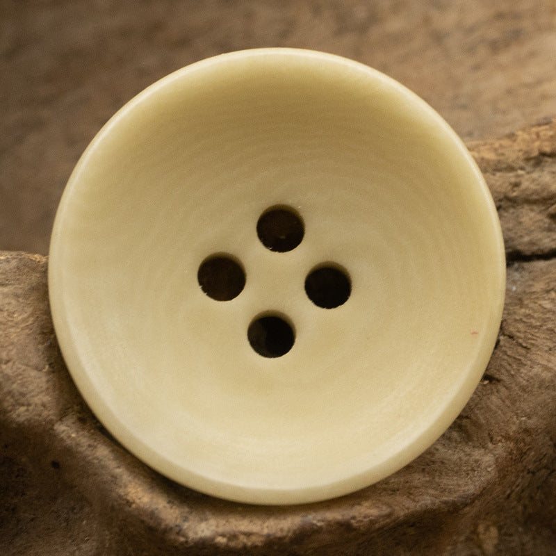 Light yellow 4-hole fruit button, smooth round face close-up
