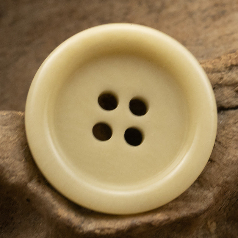 Light yellow 4-hole fruit button, round face close-up showing four holes