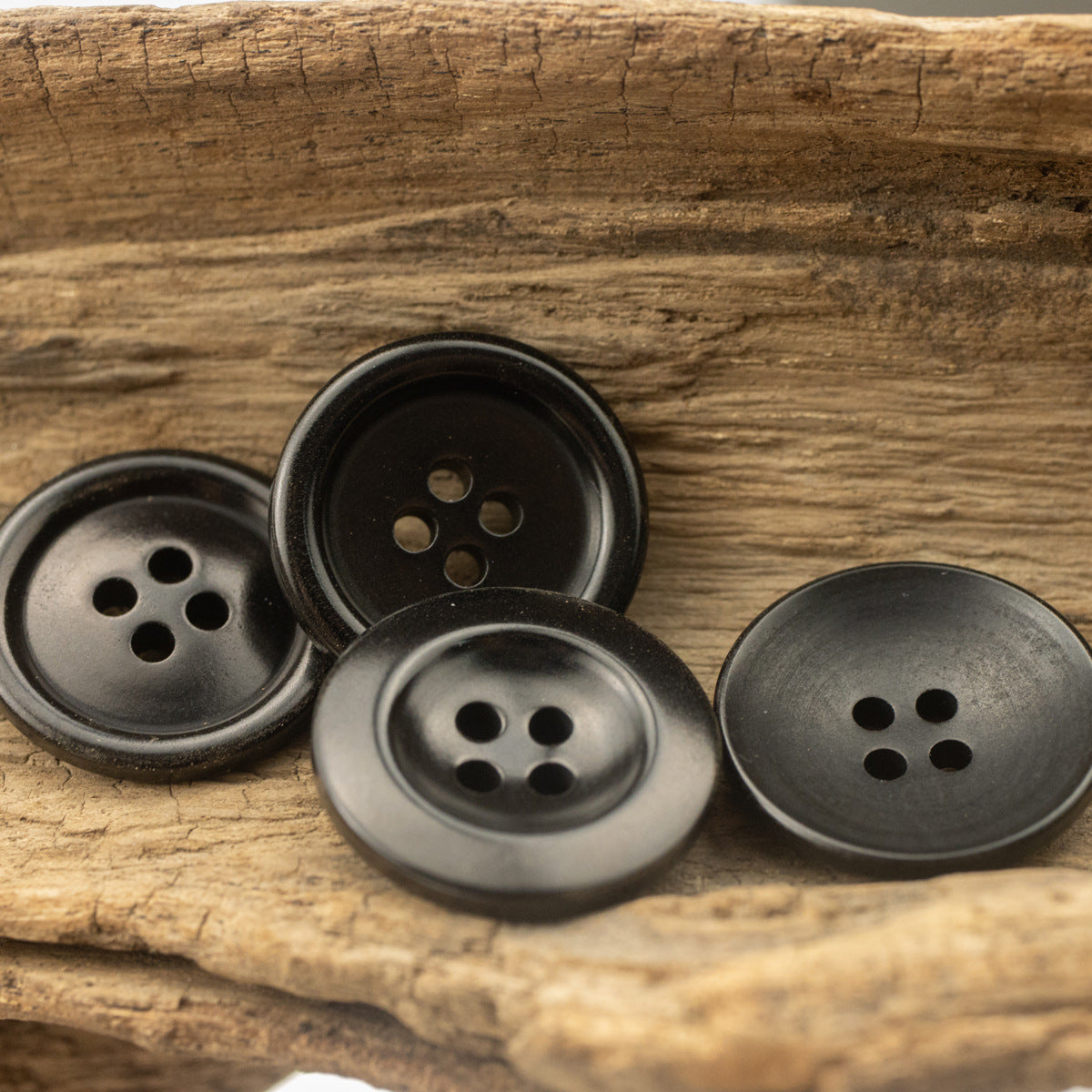Black round 4-hole buttons, mixed front views on wood surface