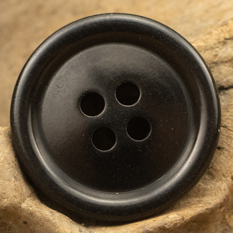 Black round button close-up, four holes on the front