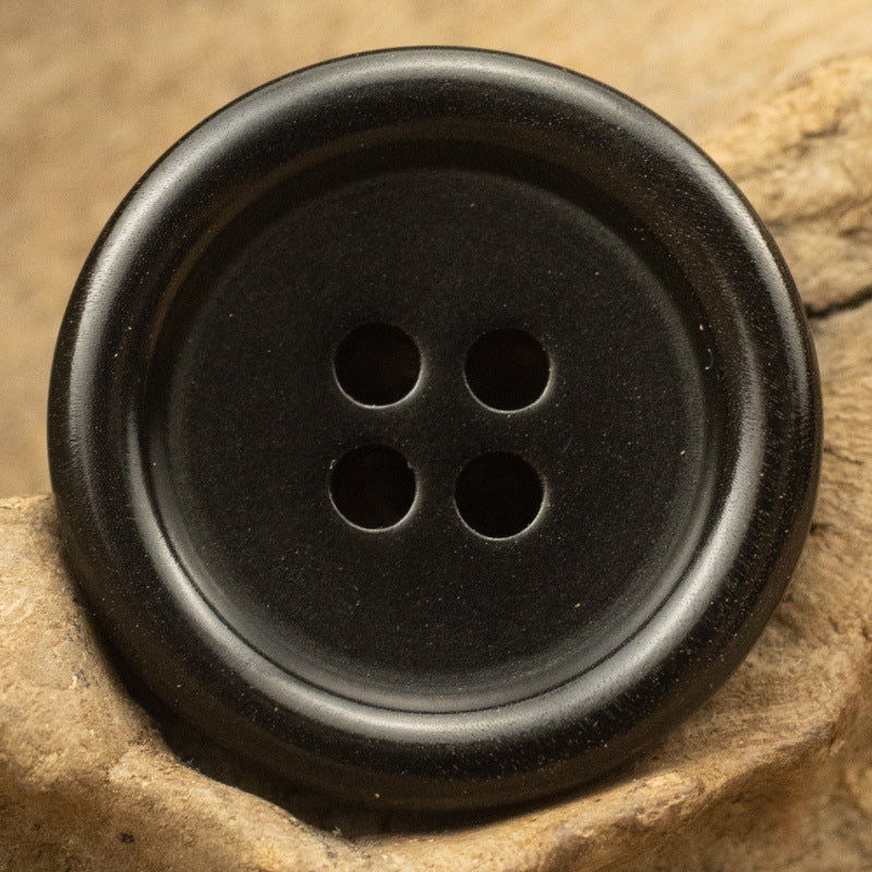 Black round button close-up, four holes centered on the face