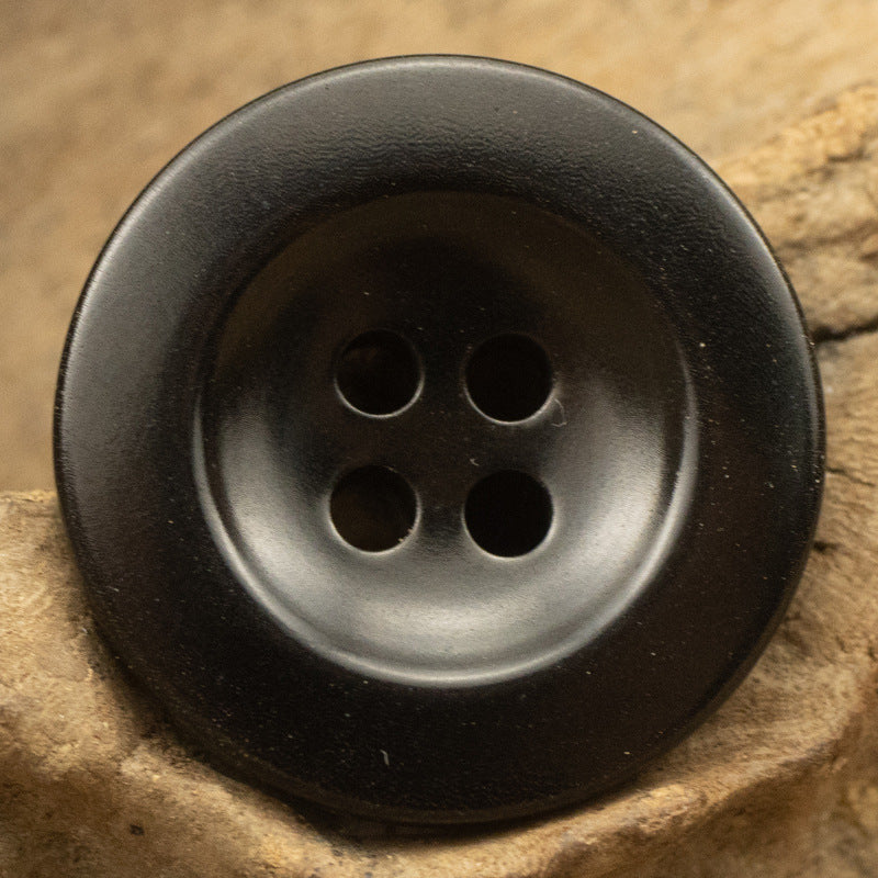 Black round button close-up, two top and two bottom holes