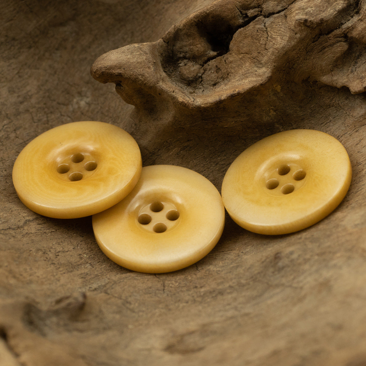 Set of three yellow four-hole buttons on a surface