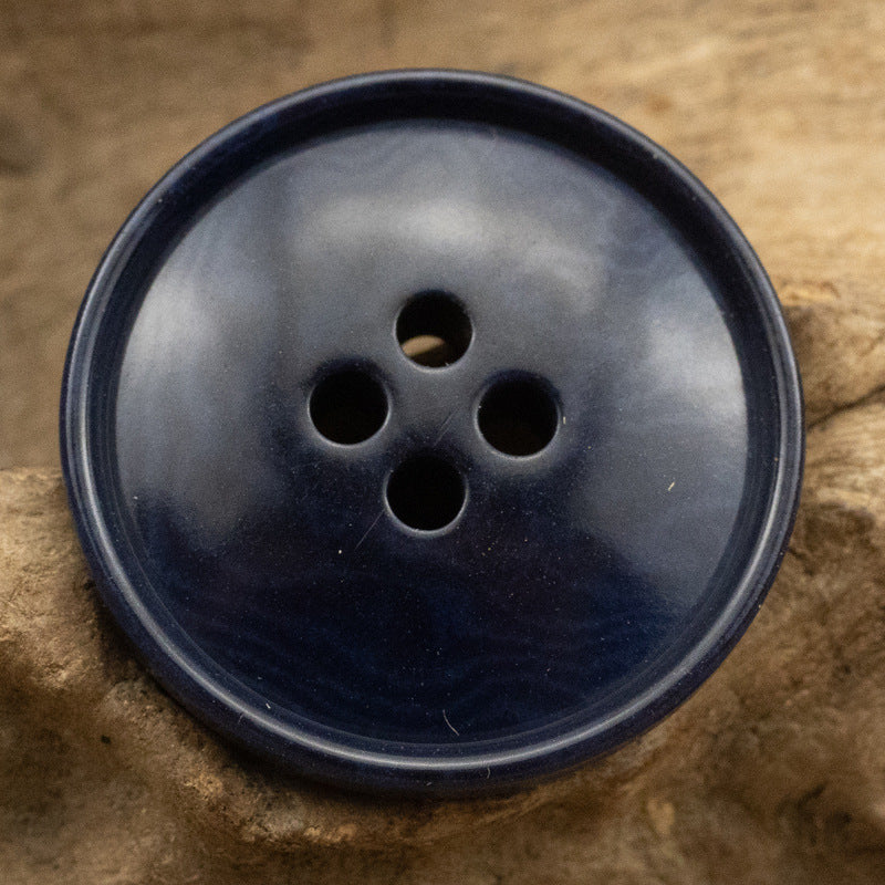 Dark blue corozo button with four holes and slim rippled edge