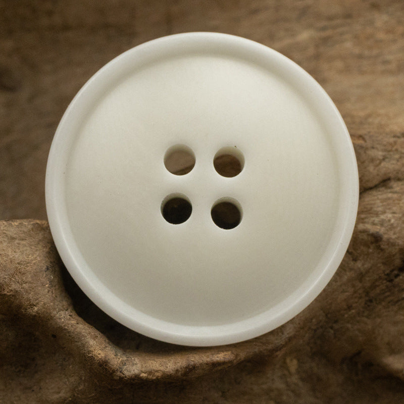 White corozo button with four holes and slim rippled edge