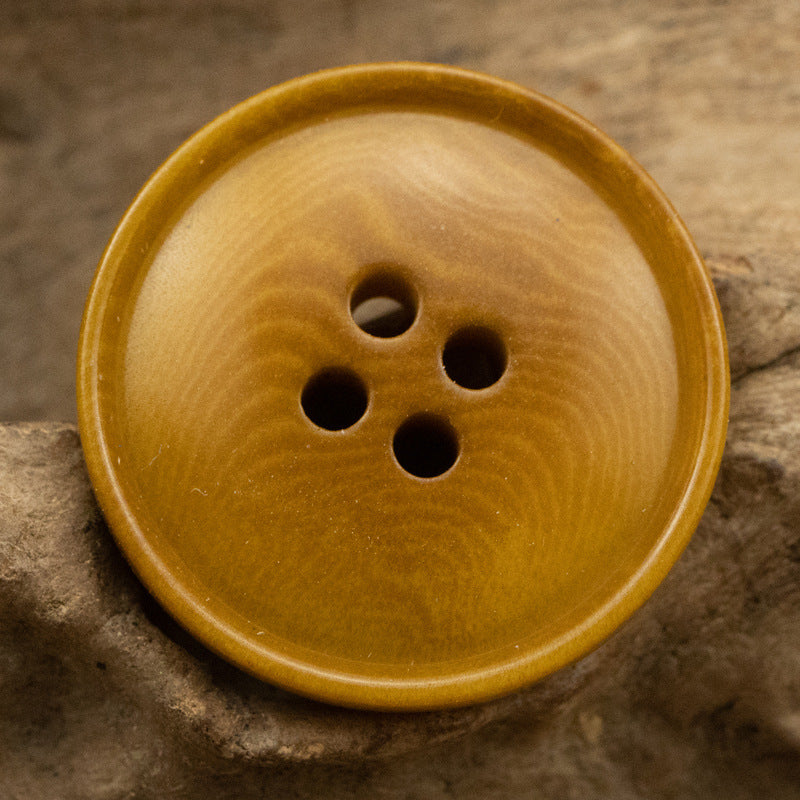 Khaki corozo button with four holes and slim rippled edge