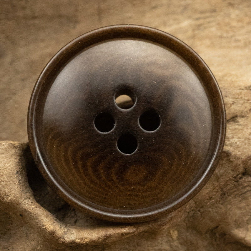 Coffee-brown corozo button with four holes and slim rippled edge
