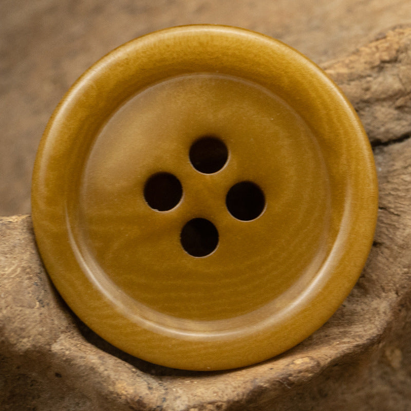 Khaki yellow 4-hole button, round face with visible woodgrain and dark holes