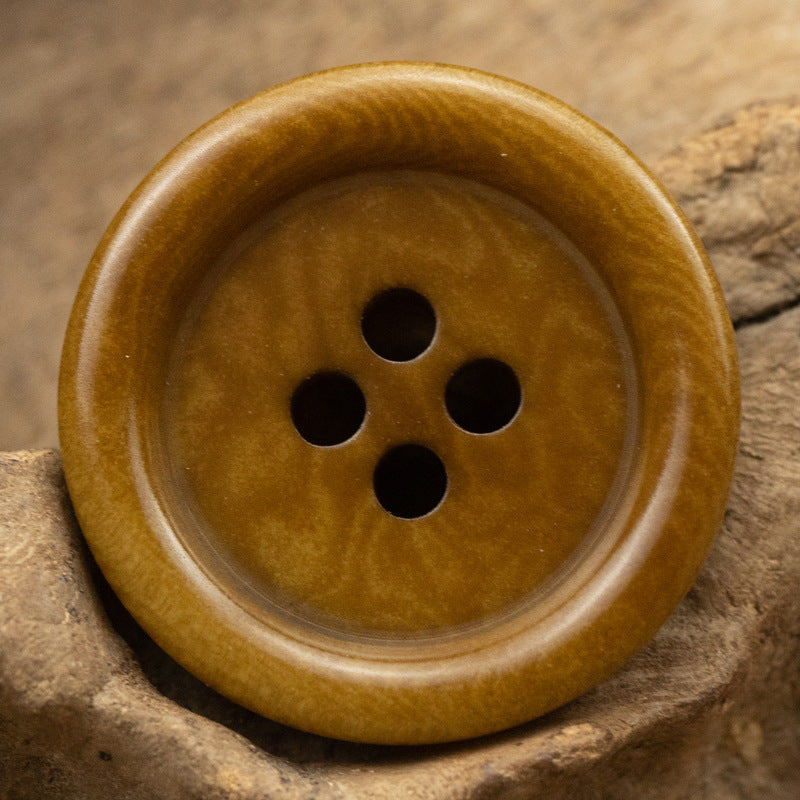 Khaki yellow 4-hole button, slightly domed face with pale rim and woodgrain