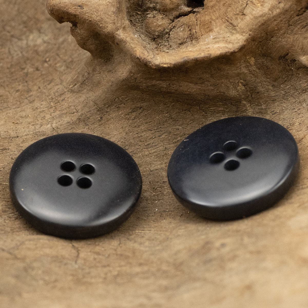 Two dark navy distressed buttons with burnished rim, five-hole design for jackets