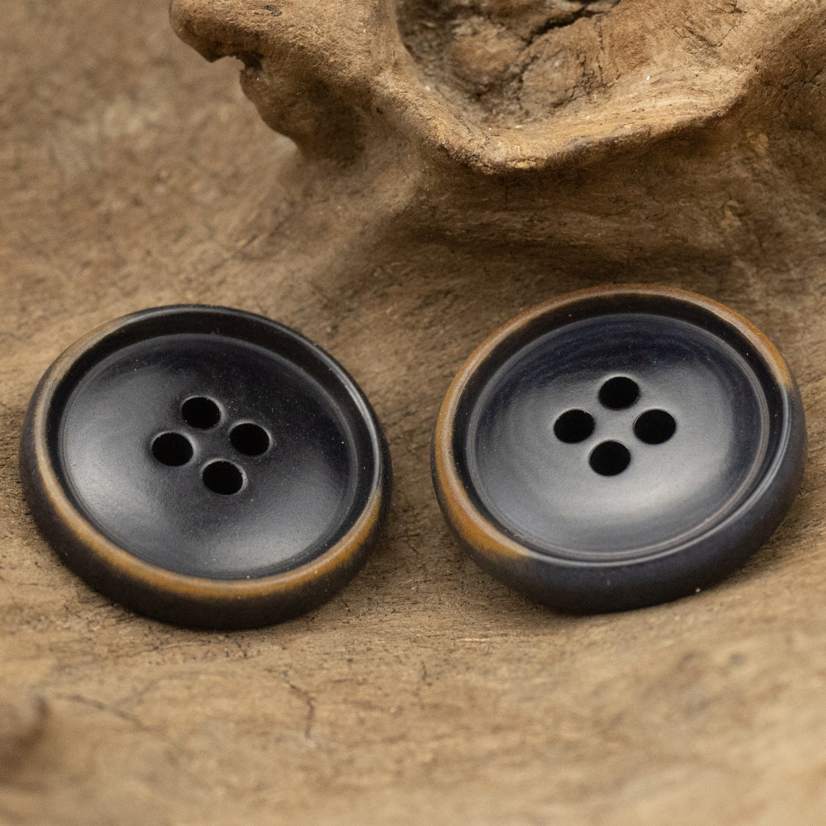 Pair of dark navy burnished-rim buttons, matte finish, four-hole front