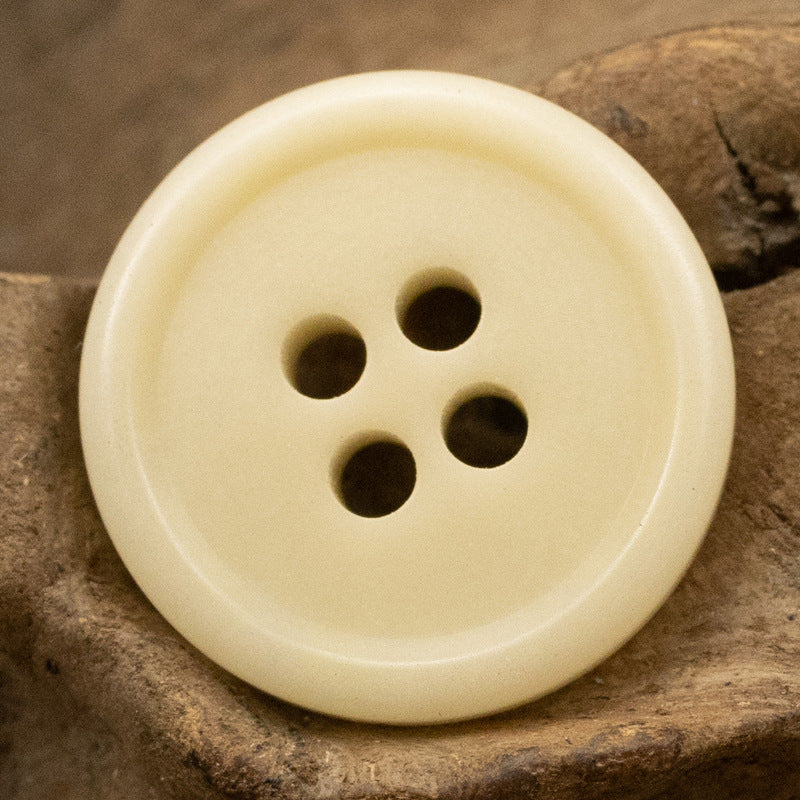 Light beige natural four-hole button with concave bowl top, close-up