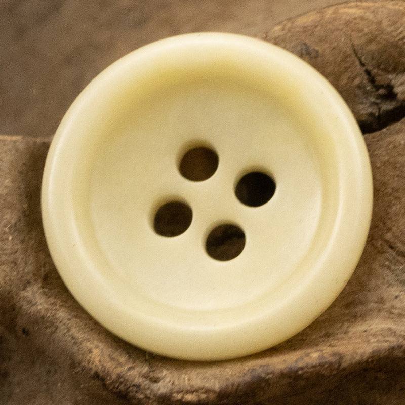 Light beige four-hole button, front view with round holes and smooth finish