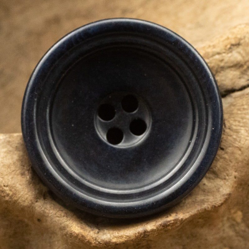 Dark blue round trouser button with 4-hole center and smooth natural sheen