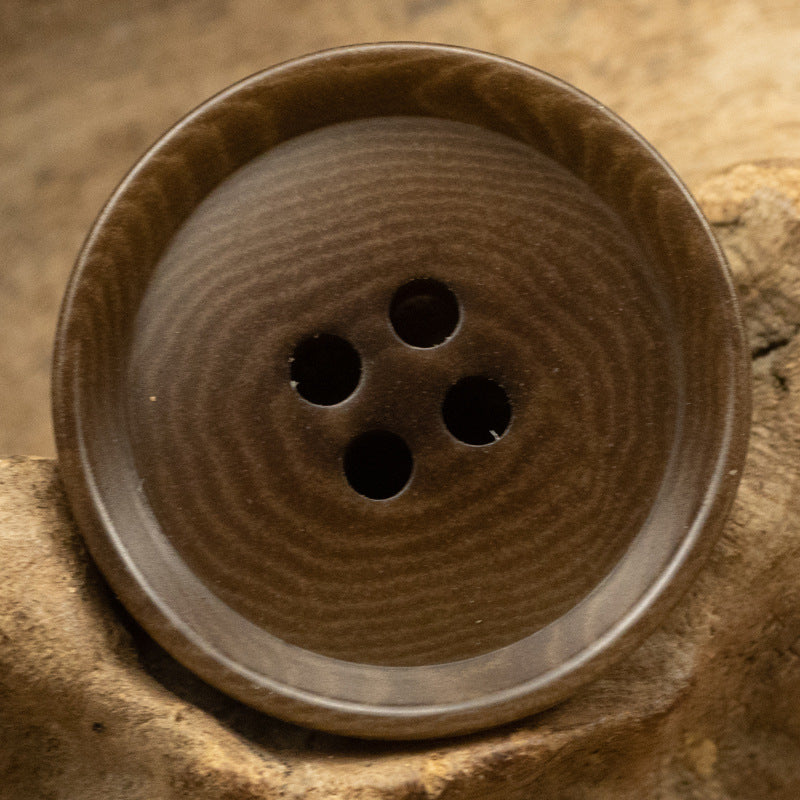 Brown four-hole tagua nut button with smooth natural swirl pattern