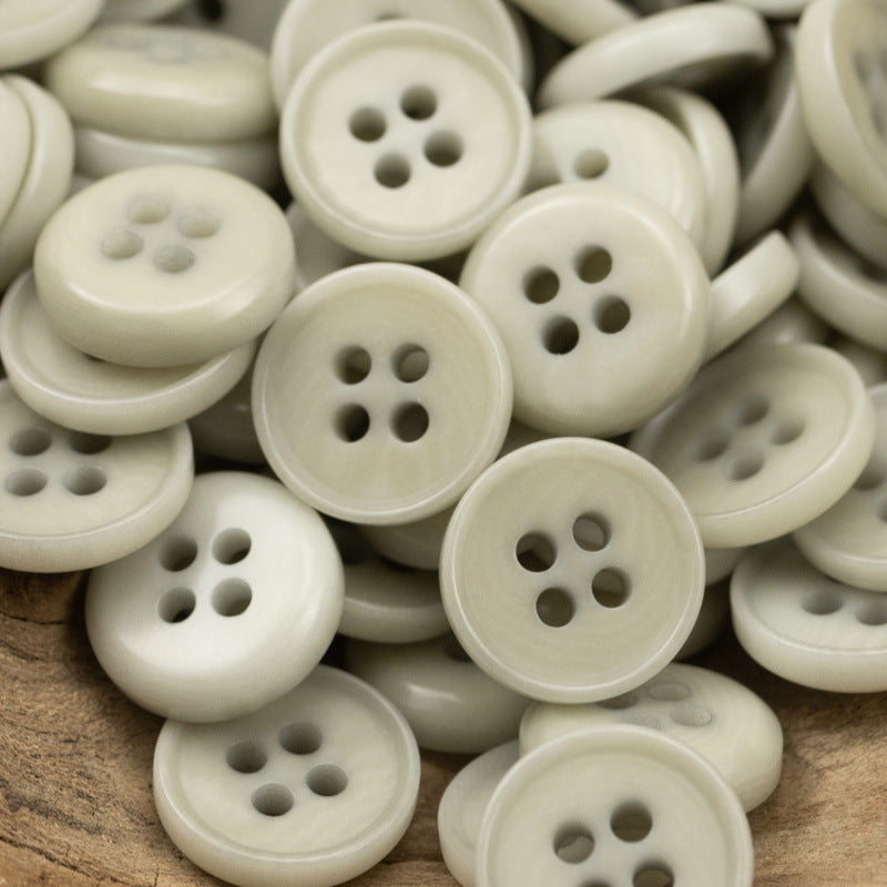 Ivory natural fruit buttons, round 4-hole design, close-up pile on a wooden surface
