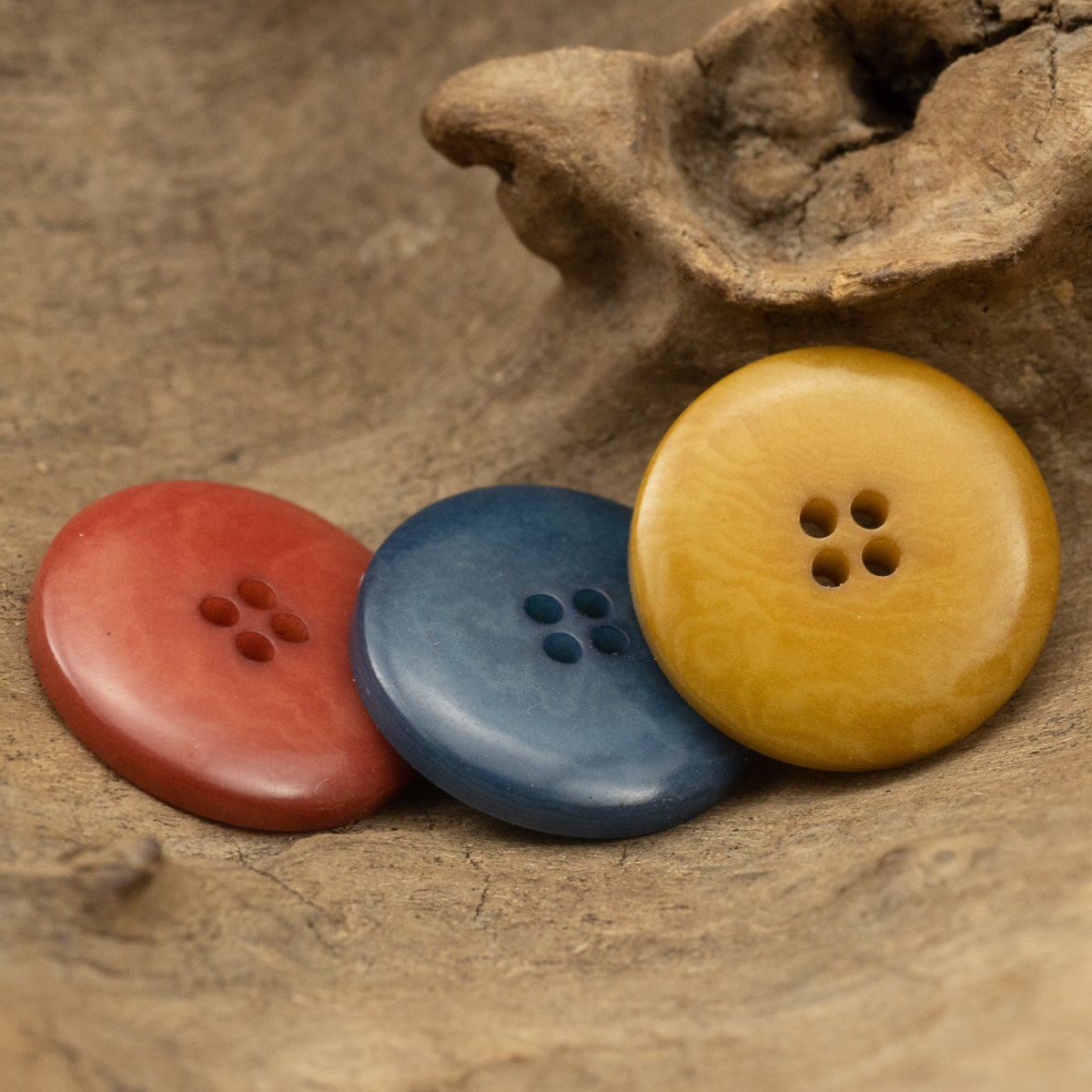 Three fruit-pattern buttons in red, blue, and yellow; each shows four holes.
