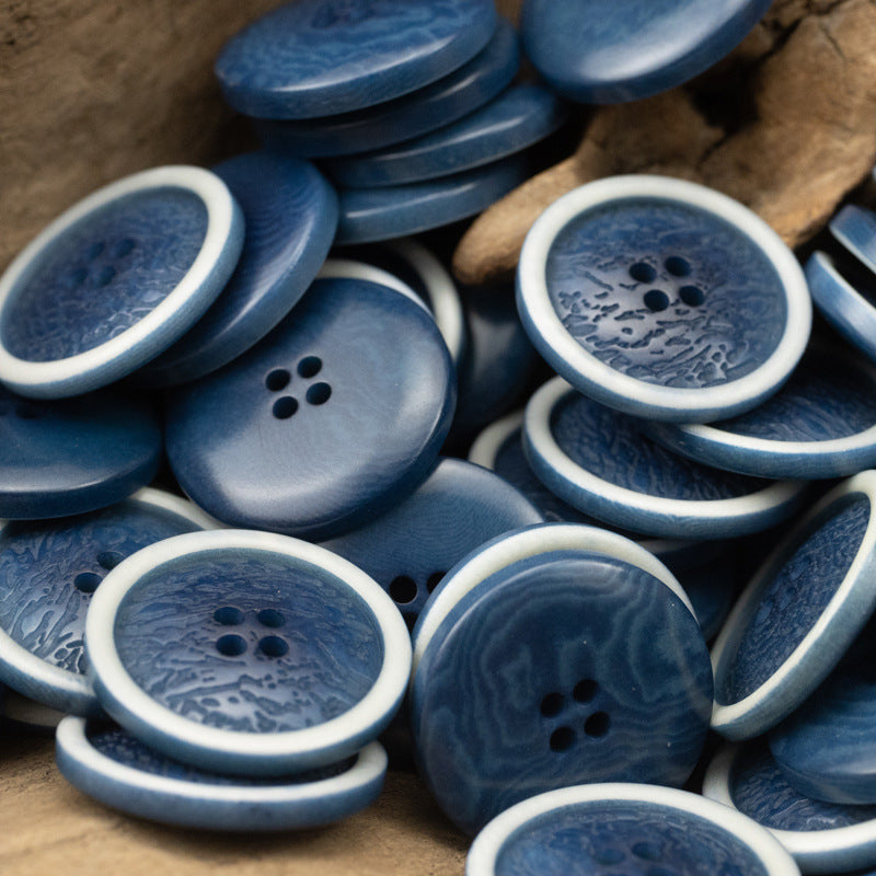 Multiple blue fruit-pattern buttons with white rims; each button has four holes.