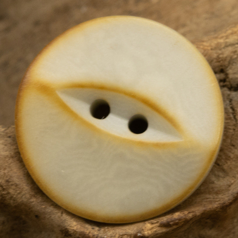Beige 2-hole nut button, vintage fish-eye swirl pattern, close-up front view