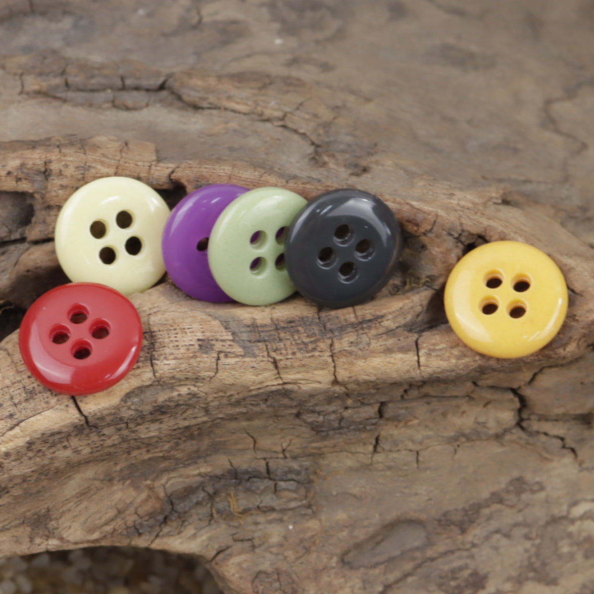 Colorful 4-hole urea buttons on wood, pastel mix: cream, purple, sage, gray, yellow