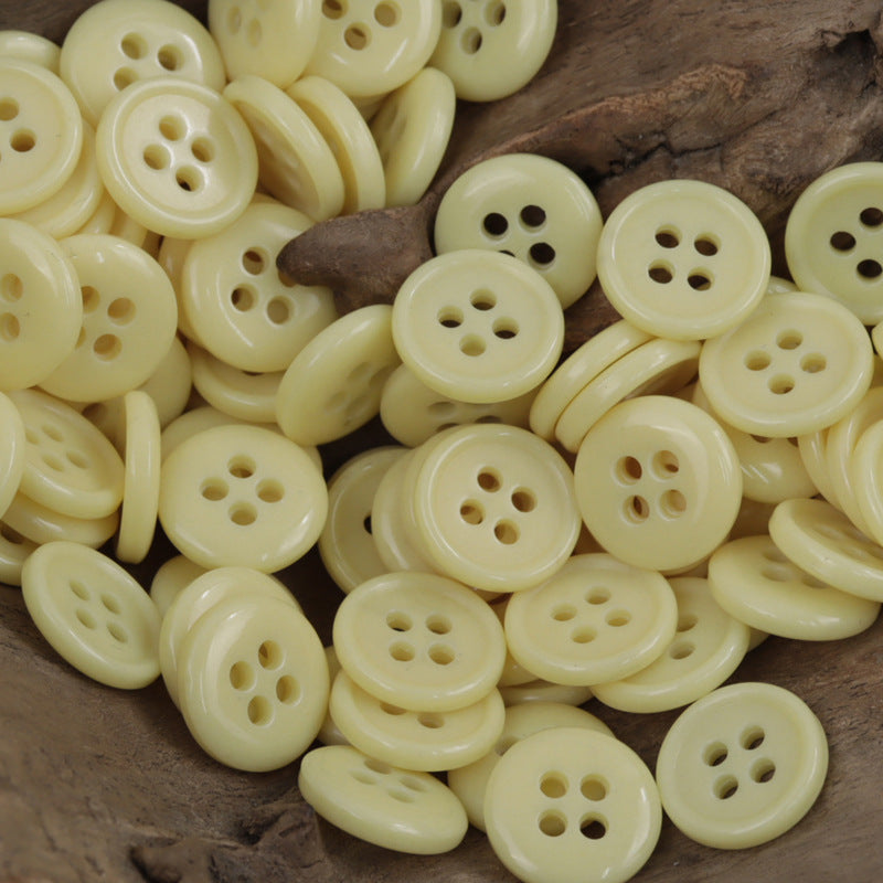 Cream/beige 4-hole urea buttons, multiple round fronts on wood surface