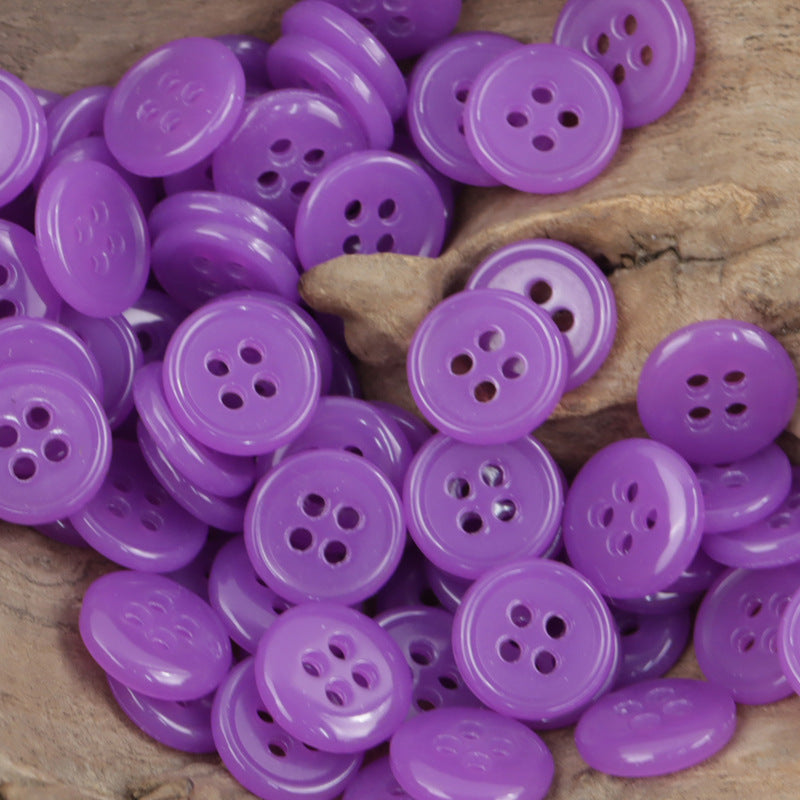 Purple 4-hole urea buttons, assorted round fronts on wood surface