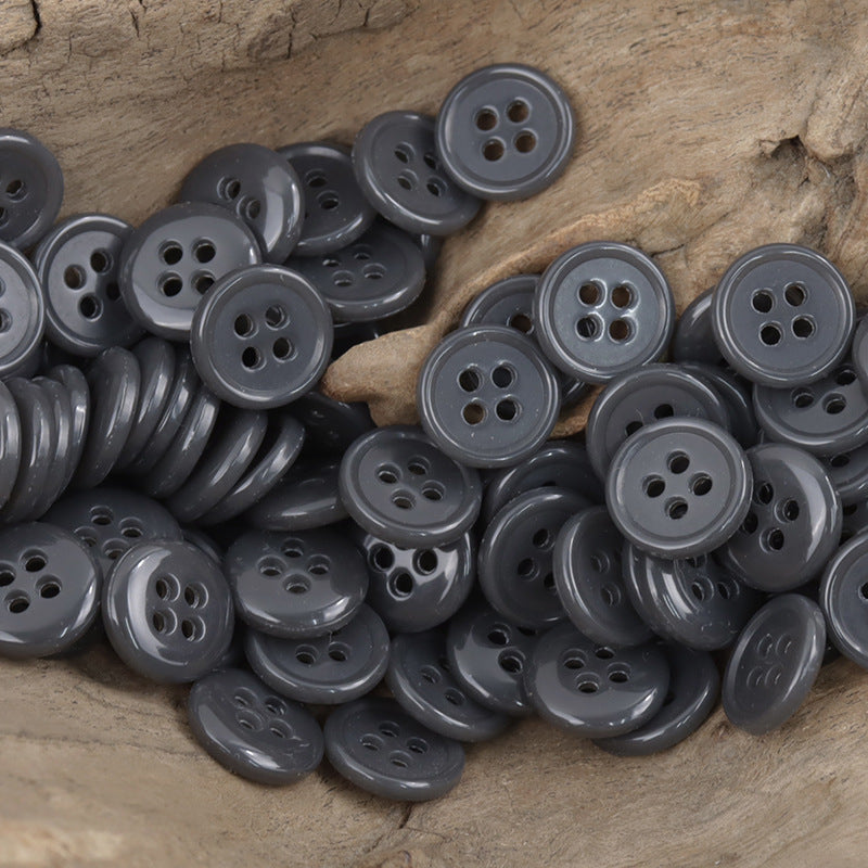 Gray 4-hole urea buttons, assorted round fronts on wood surface