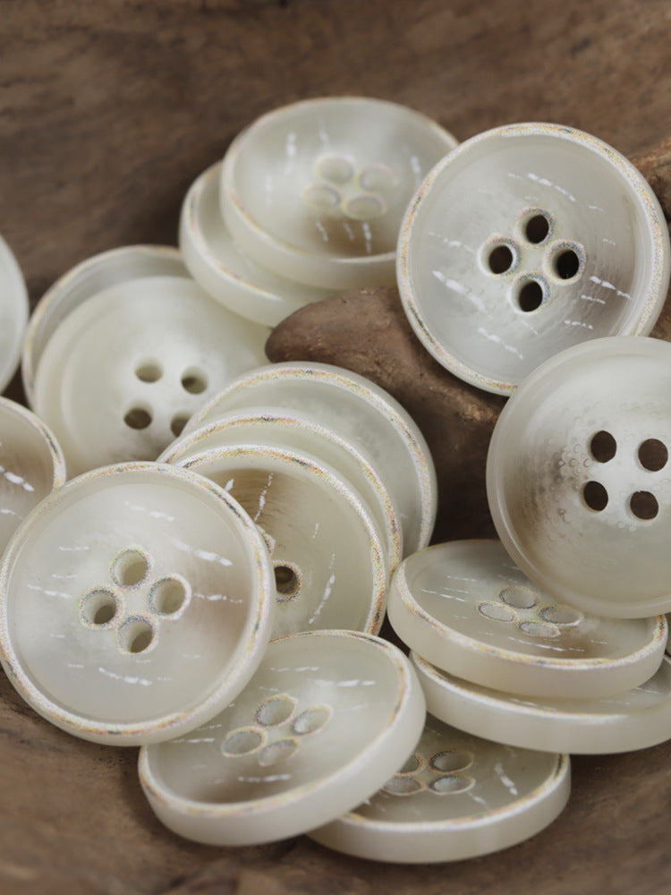 Off-white resin four-hole buttons, glossy finish with visible rim detail