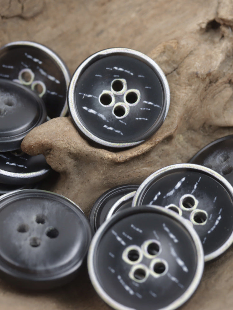 Dark charcoal resin four-hole buttons, glossy, multiple buttons in a pile