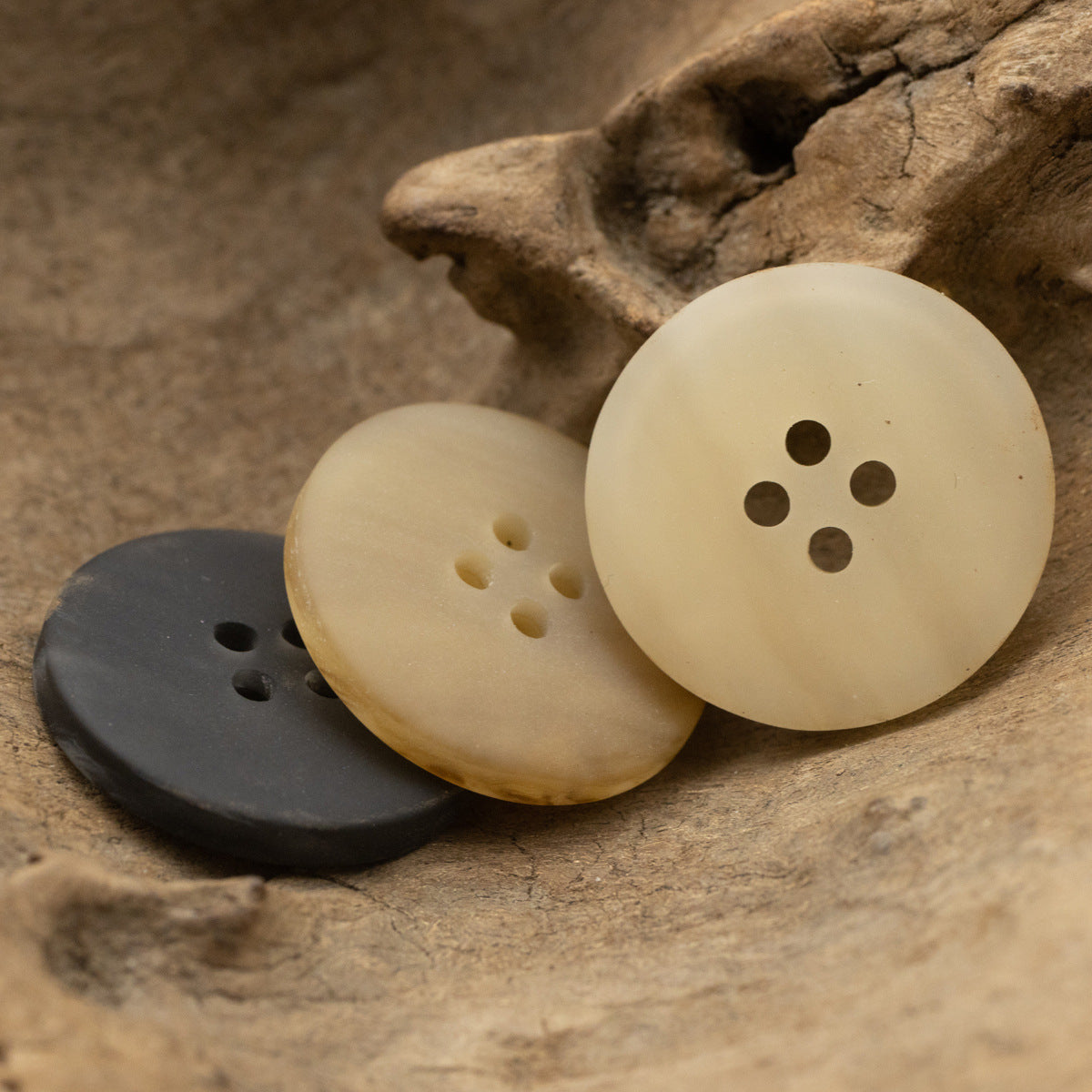 Three resin wood-grain buttons in charcoal and cream tones, four-hole phoenix groove