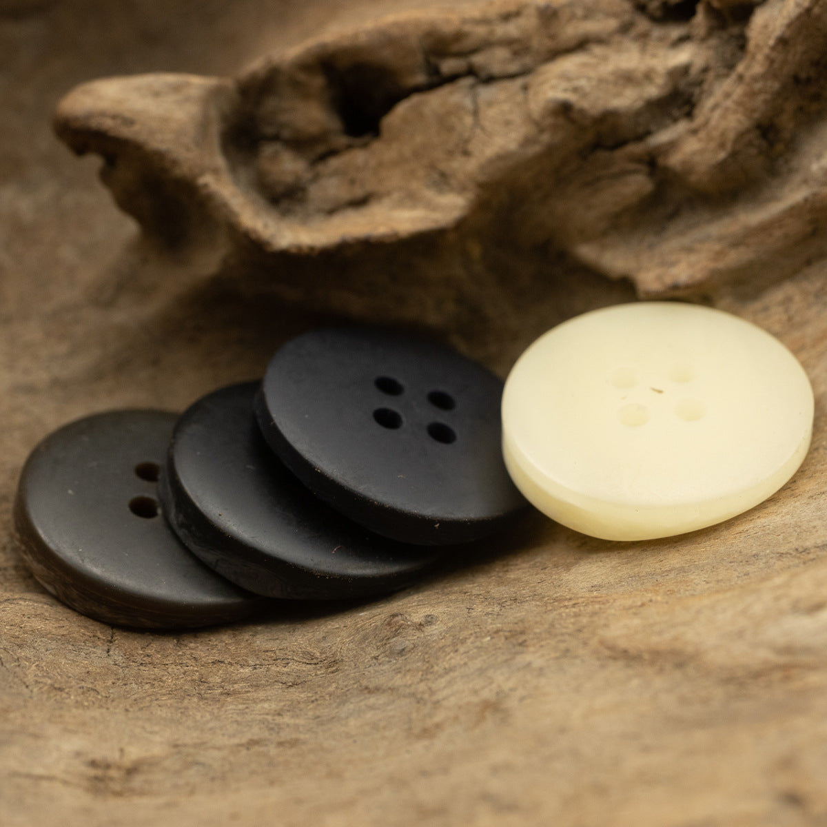 Flat resin coat buttons with irregular texture, round 4-hole designs in dark and cream