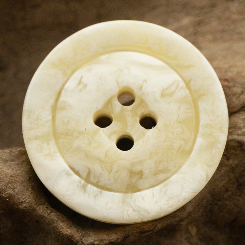 Milky coffee-colored marbled resin button with wide rim and five holes, front view