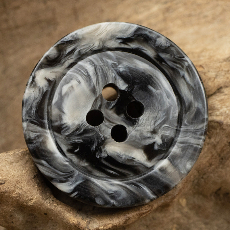 Dark charcoal marbled resin button with wide rim, five holes, close-up front view
