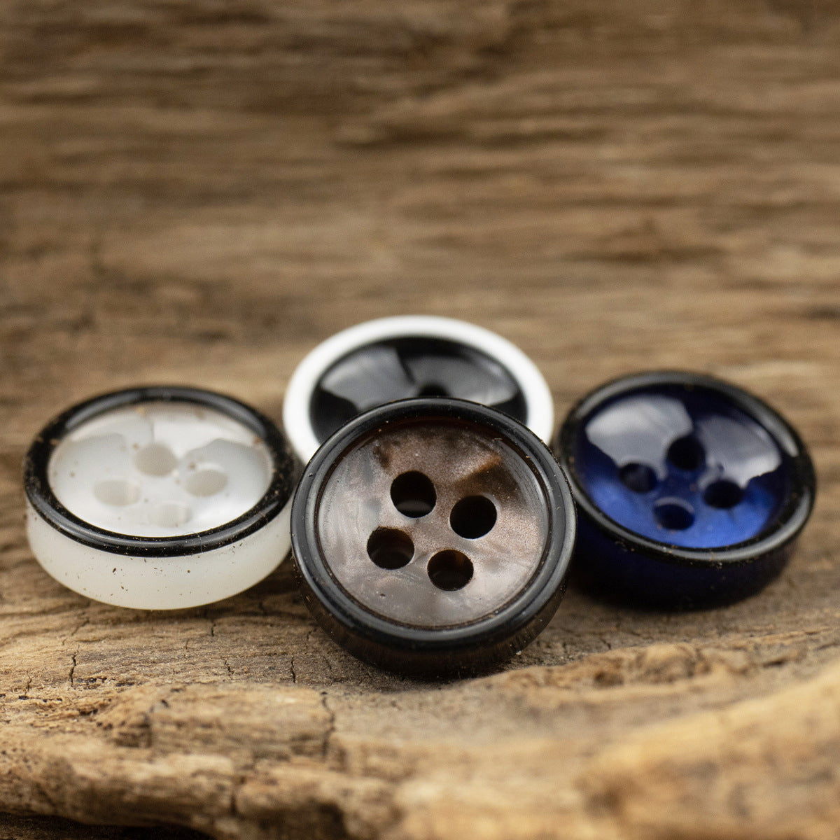 Resin 4-hole shirt buttons: white, dark gray-brown, and dark blue, shown from above