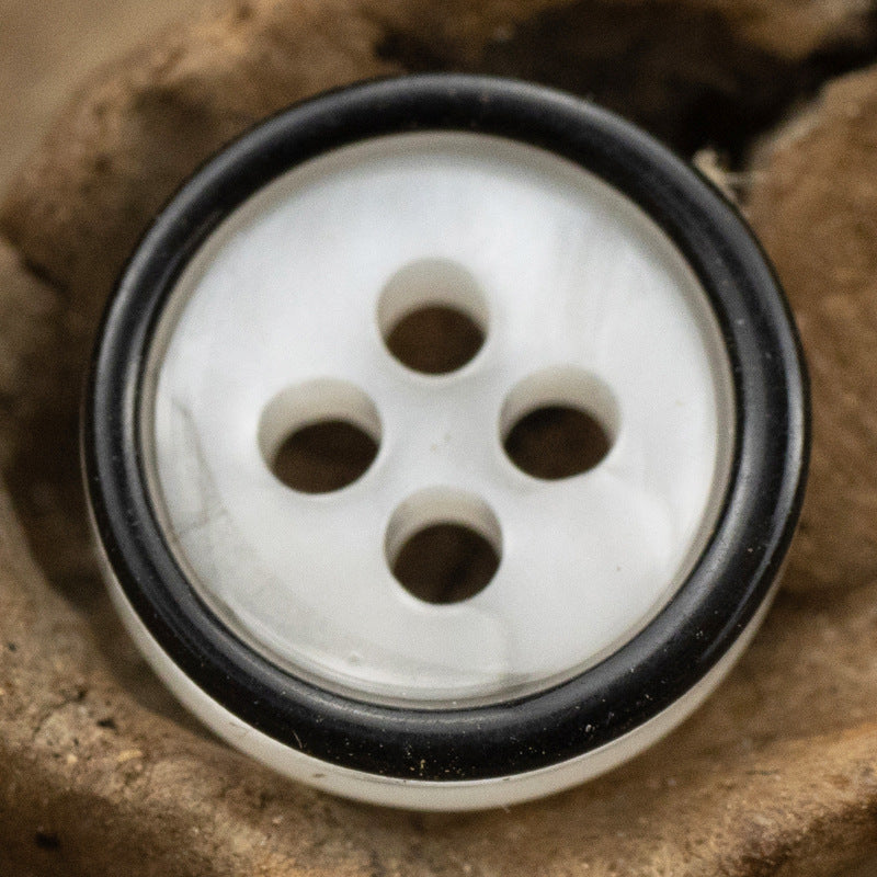 Close-up white 4-hole resin shirt button with black rim