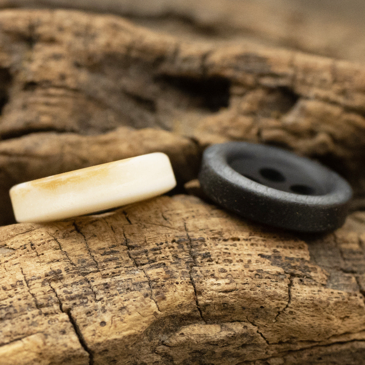 Light yellow 4-hole resin button with black button beside, wood grain look
