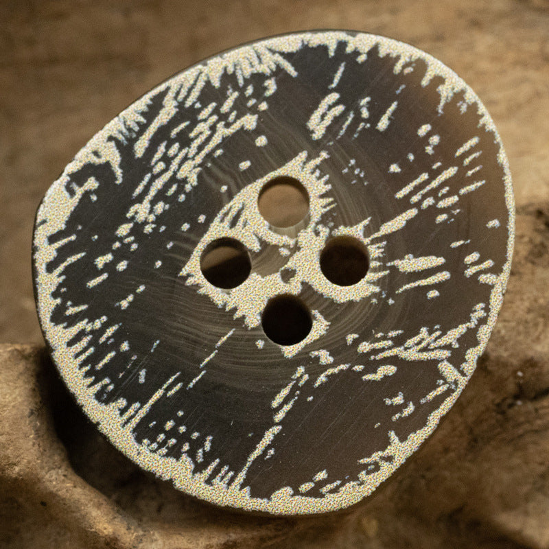 Dark gray resin button with four holes and distressed frosted floral speckle