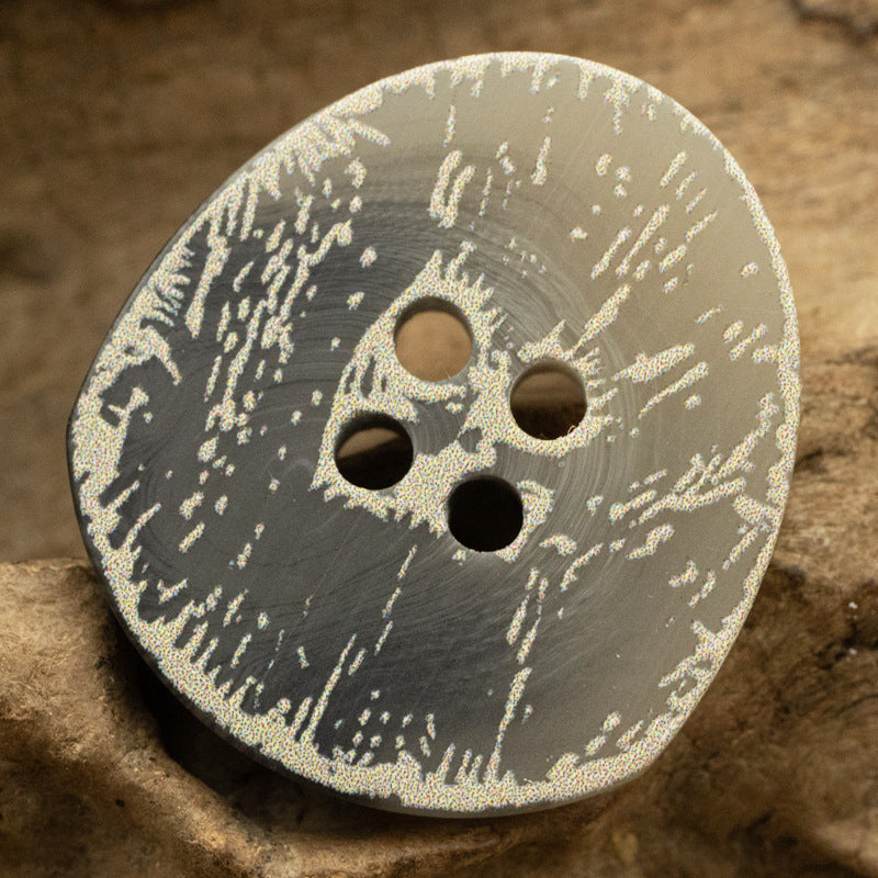 Dark resin button with four holes, irregular distressed frosted floral design
