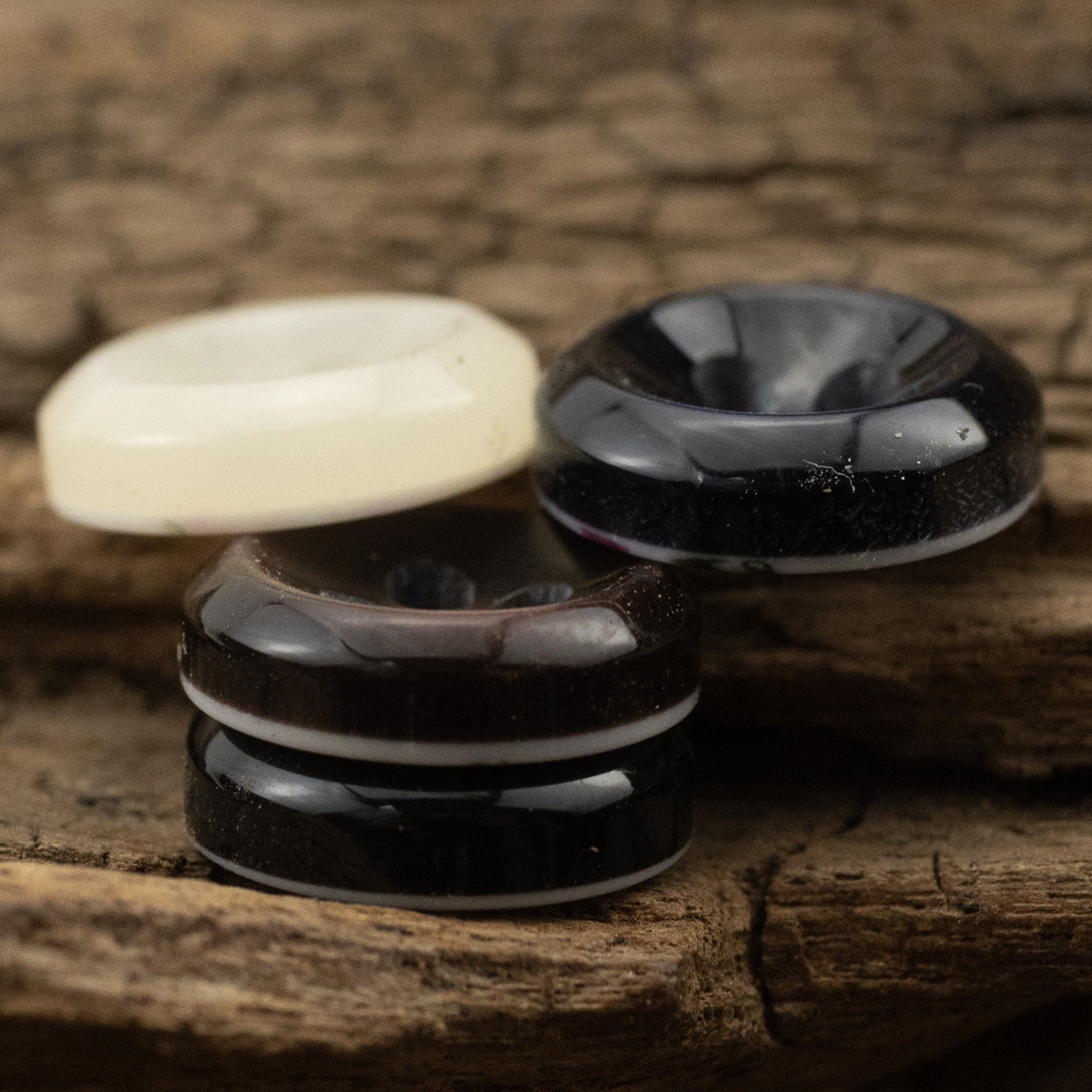 Stacked pearlized resin buttons, side view: white and dark (blue/black)