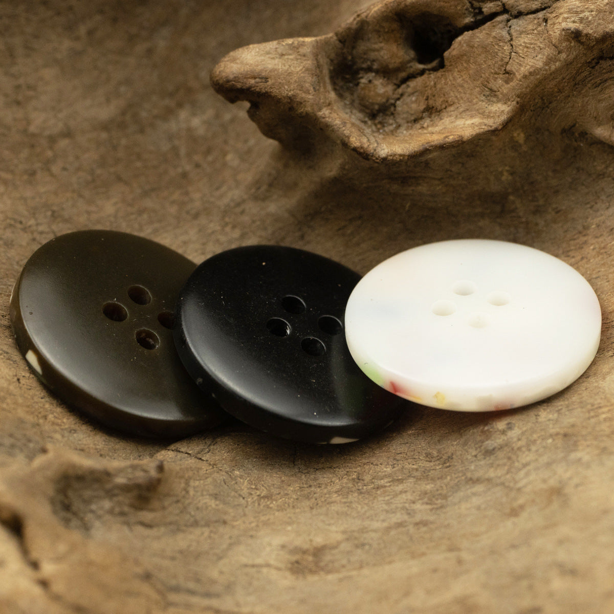 Assorted resin buttons in dark brown, black, and white tones with four holes