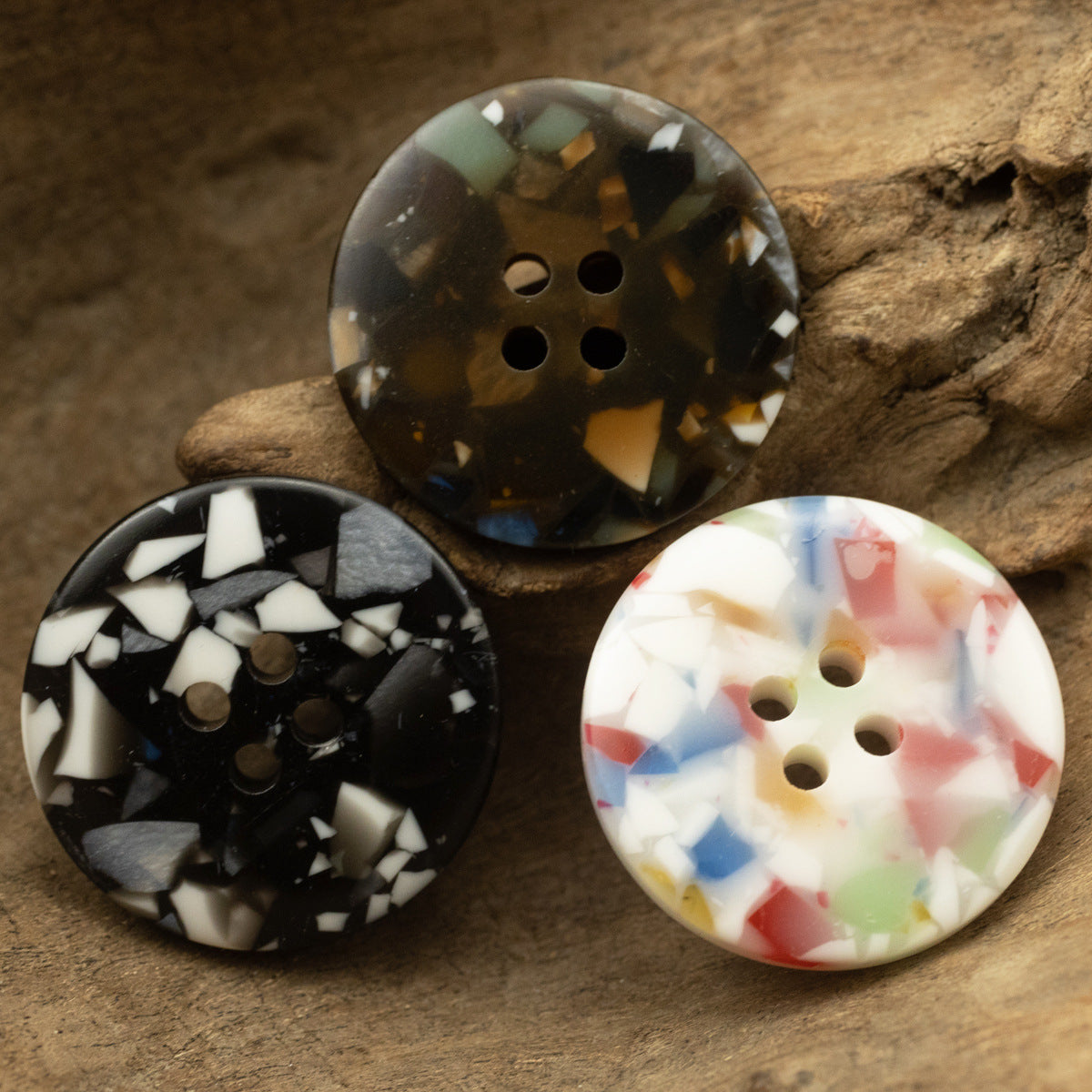 Four-hole resin buttons in dark, black/white mosaic, and cream floral glass