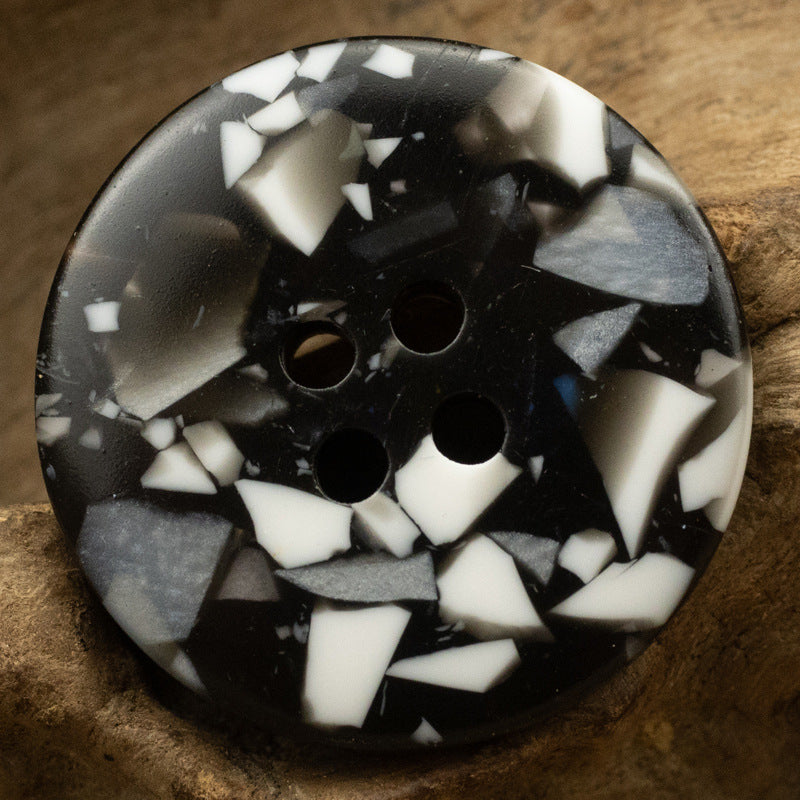 Black resin button with white mosaic floral-glass texture and four holes