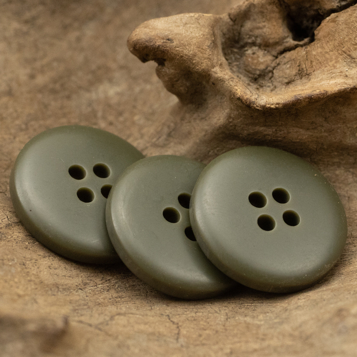Matte army green 4-hole round resin buttons in angled view