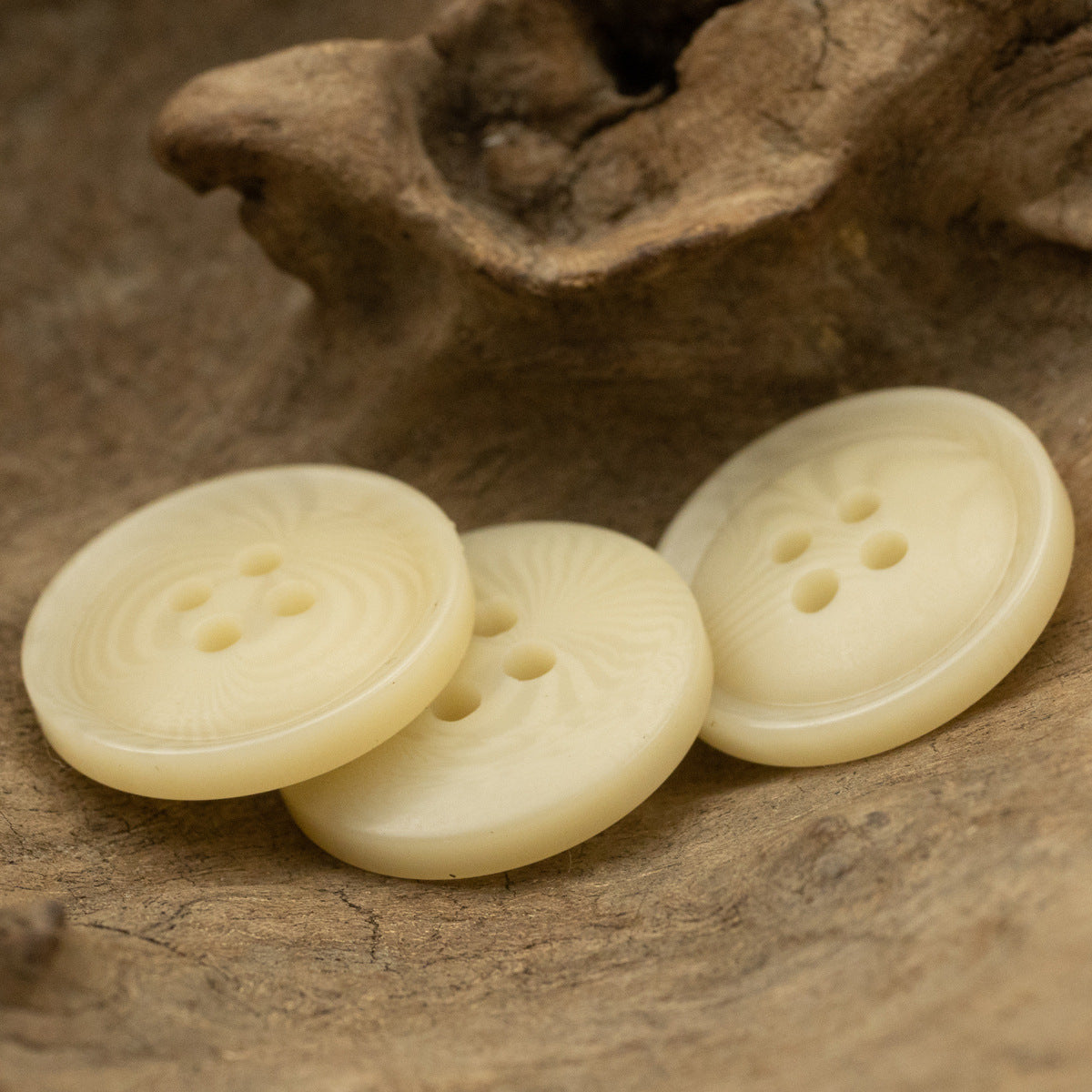 Three pale-yellow resin buttons with 4-hole fronts and textured fruit-like surface